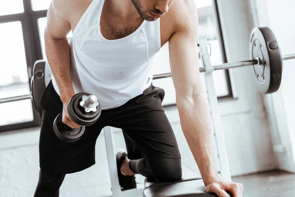 Vista recortada del hombre barbudo haciendo ejercicio con pesadas mancuernas en el gimnasio - foto de stock