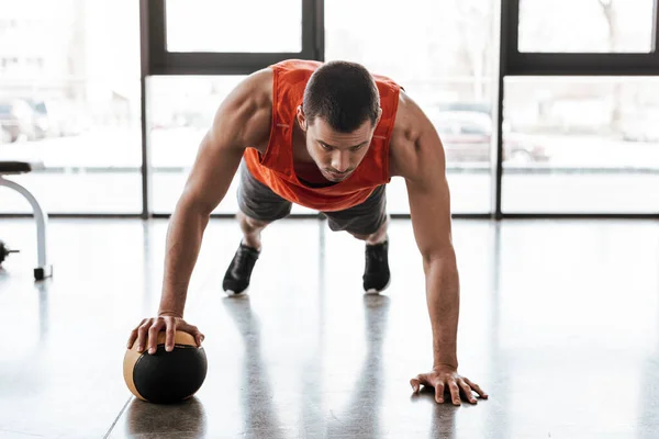 Handsome sportsman doing plank exercising with ball — Stock Photo
