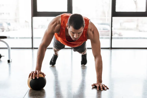 Beau sportif faisant de l'exercice de planche avec balle — Photo de stock