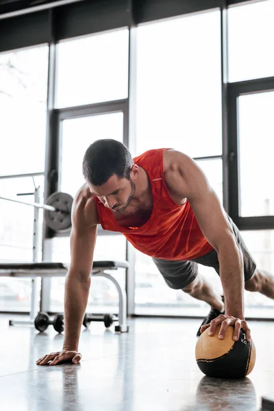 Сильный спортсмен делает доску упражнения с мячом — стоковое фото