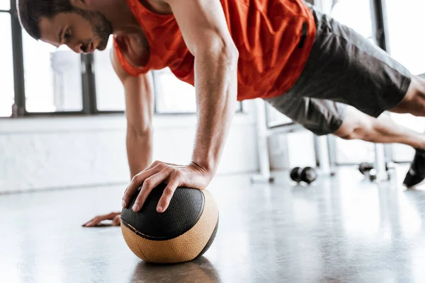 Enfoque selectivo de deportista guapo haciendo ejercicio de tablón con pelota - foto de stock