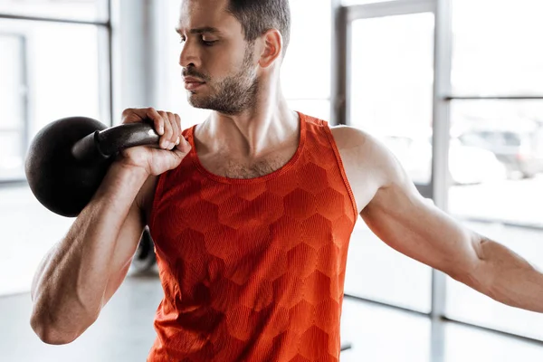 Forte desportista exercitando e olhando para halteres pesados — Fotografia de Stock