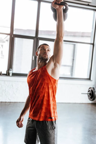 Strong sportsman holding heavy dumbbell above head while exercising in gym — Stock Photo