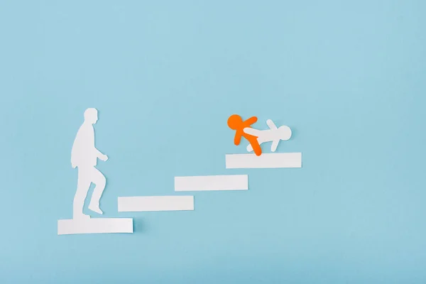 Вид зверху на паперових помаранчевих і білих чоловіків на кар'єрних сходах на синьому — стокове фото