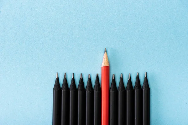 Вид сверху красного карандаша среди черного на синем фоне — стоковое фото