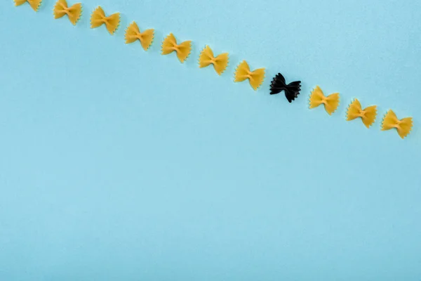 Draufsicht auf schwarze Pasta zwischen gelb auf blauem Hintergrund — Stockfoto