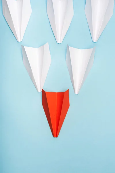 Top view of unique red paper plane among white on blue background — Stock Photo