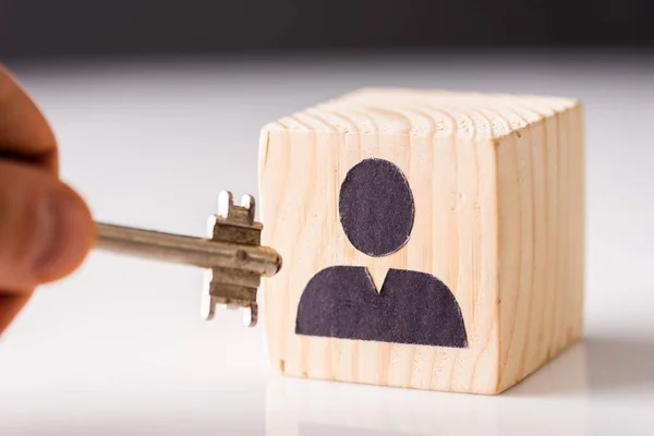 Cropped view of man putting key in cube with painted man on white and black — Stock Photo