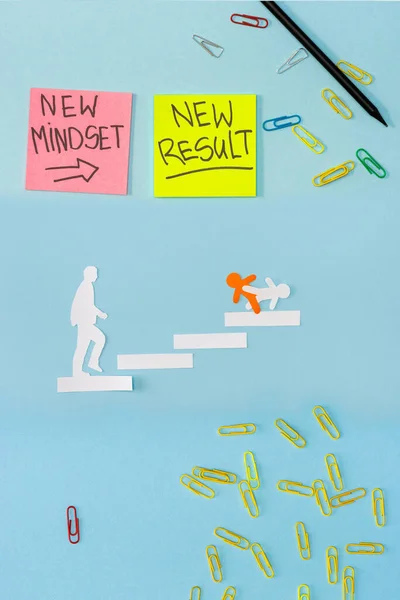 Top view of sticky notes with new mindset and new result lettering with paper clips, pencil and decorative men on career ladder on blue — Stock Photo