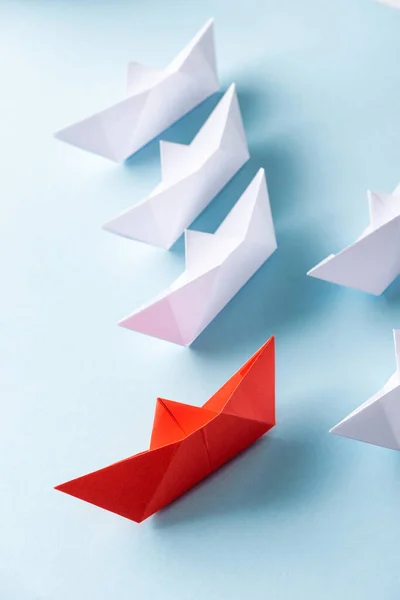 Top view of unique red paper boat among white on blue — Stock Photo