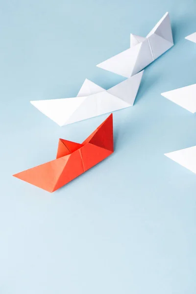High angle view of unique red paper boat among white on blue background — Stock Photo