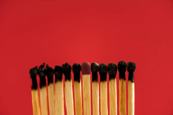 Match among burned matches isolated on red — Stock Photo