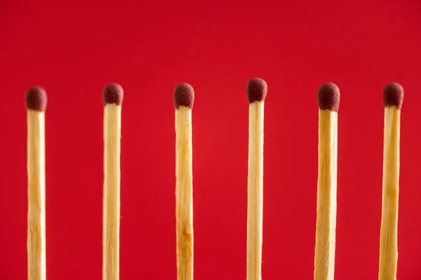 Línea con fósforos de madera aislados en rojo - foto de stock