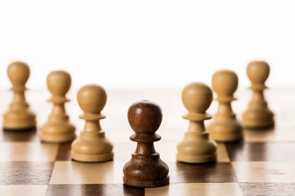 Foco seletivo de peão marrom entre outros no tabuleiro de xadrez isolado em branco — Fotografia de Stock