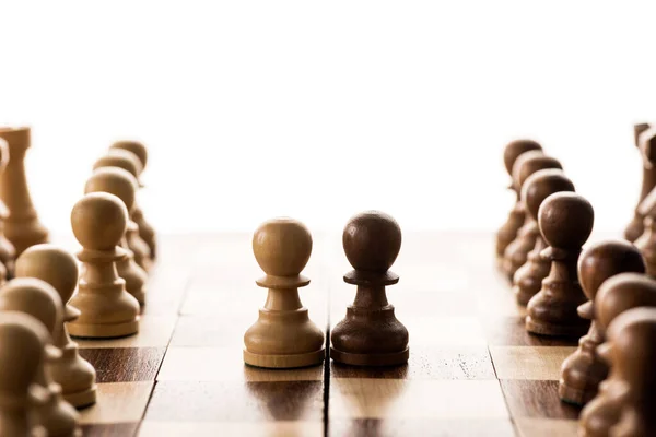 Selective focus of brown pawn against another on chessboard isolated on white — Stock Photo