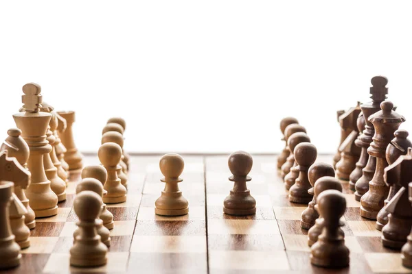 Selective focus of chess pieces and brown pawn against another on chessboard isolated on white — Stock Photo