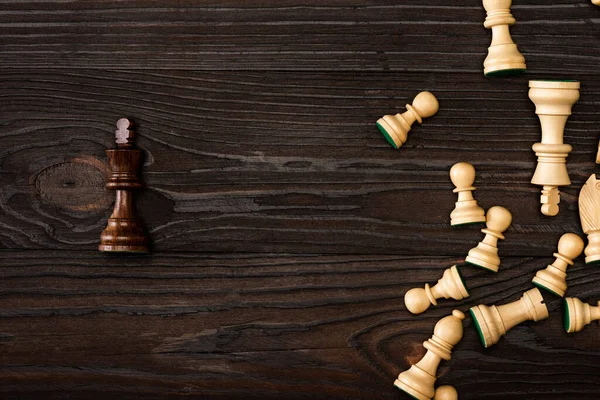 Vue de dessus du roi brun unique avec des pièces d'échecs blanches sur fond en bois — Photo de stock