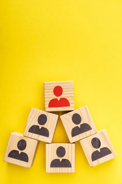 Top view of wooden cubes with red painted man among another on yellow background — Stock Photo