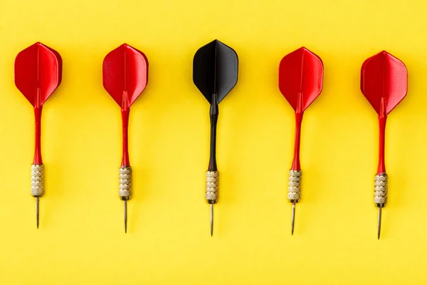 Flat lay with black dart among red on yellow — Stock Photo