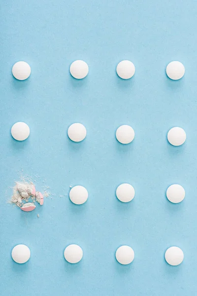 Draufsicht auf zerquetschte Pille zwischen ganzen Pillen auf blau — Stockfoto