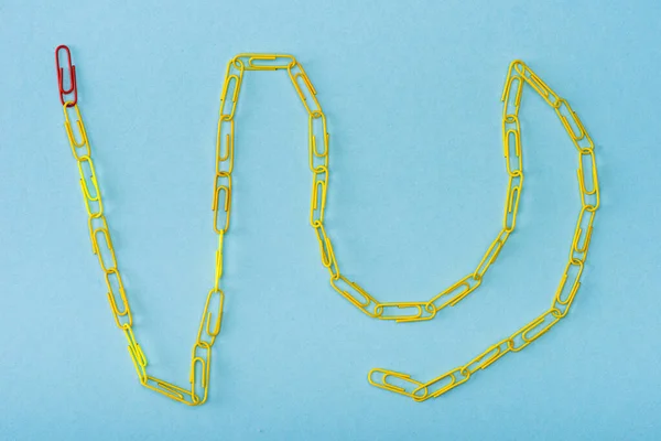 Top view of chain with unique red and yellow paper clips on blue — Stock Photo