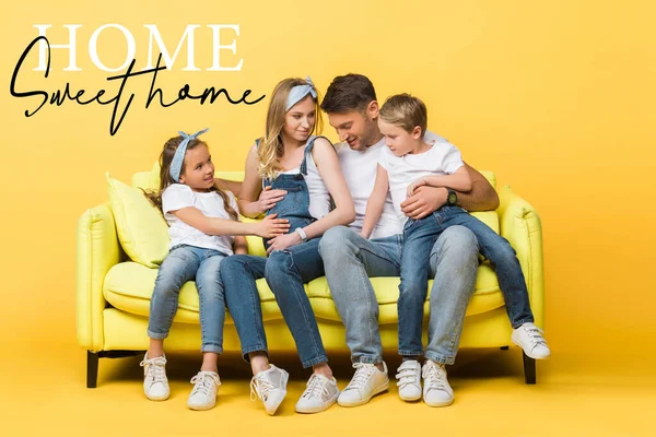Эмоциональная беременная жена, муж и дети сидят на диване на желтом, дома сладкий дом иллюстрации — стоковое фото