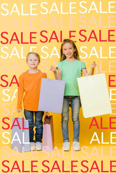 Adorable smiling kids holding shopping bags on yellow, sale illustration — Stock Photo