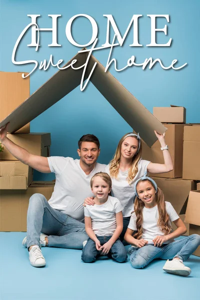 Positive parents holding carton roof over kids on blue with cardboard boxes for relocation, home sweet home illustration — Stock Photo