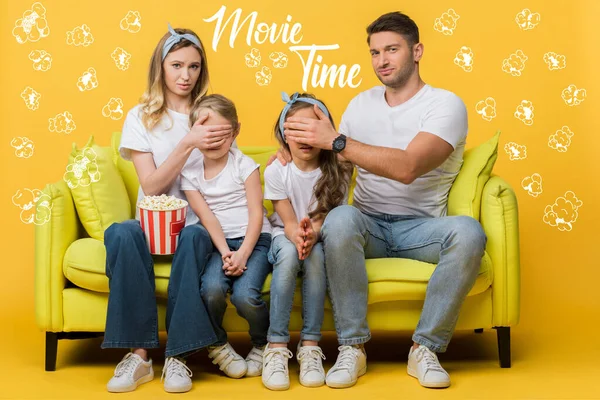 Padres escépticos cerrando los ojos a los niños mientras ven películas en el sofá con cubo de palomitas de maíz en amarillo, tiempo de película e ilustración de palomitas de maíz - foto de stock