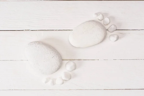 Top view of feet from sea stones on white wooden planks — Stock Photo