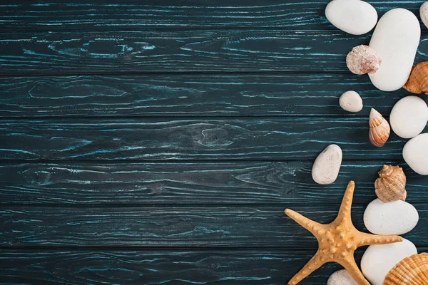 Vue du dessus des cailloux avec étoiles de mer et coquillages sur fond de bois sombre avec espace de copie — Photo de stock