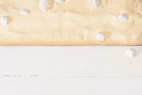 Top view of white wooden planks near sea stones on textured sand — Stock Photo