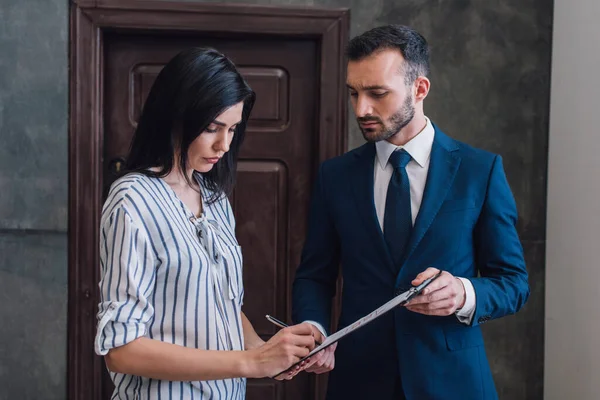 Donna che scrive in documenti in mani maschili in camera — Foto stock