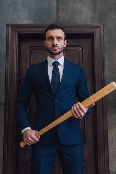 Angry collector with baseball bat near door in room — Stock Photo