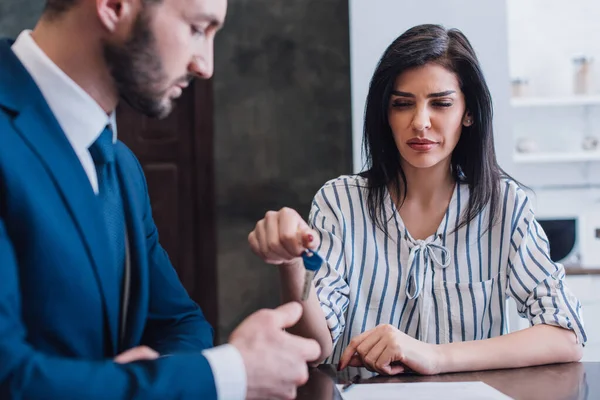 Selective focus of woman giving key to collector at table in room — Stock Photo