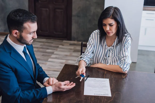 High angle view of woman giving keys to collector at table with pen and document in room — Stock Photo