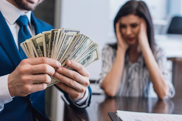 Selective focus of collector with money near stressed woman at table in room — Stock Photo