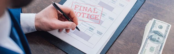 Cropped view of collector writing in documents with final notice near dollar banknotes at table, panoramic shot — Stock Photo