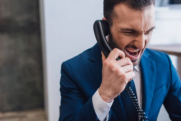 Wütender Sammler hält Hörer in der Hand und schreit im Raum — Stockfoto