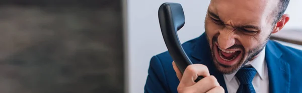 Panoramic crop of angry collector shouting on handset in room — Stock Photo