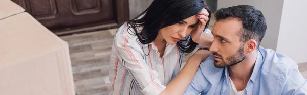 Panoramic shot of upset bankrupts looking at each other near boxes on floor — Stock Photo