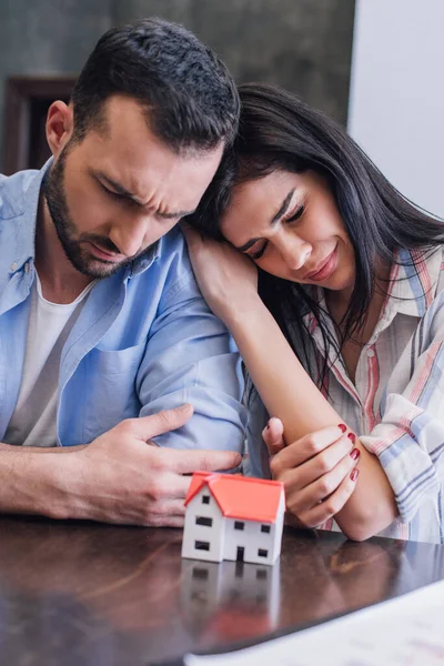 Woman crying and leaning to tense man near house model at table — Stock Photo