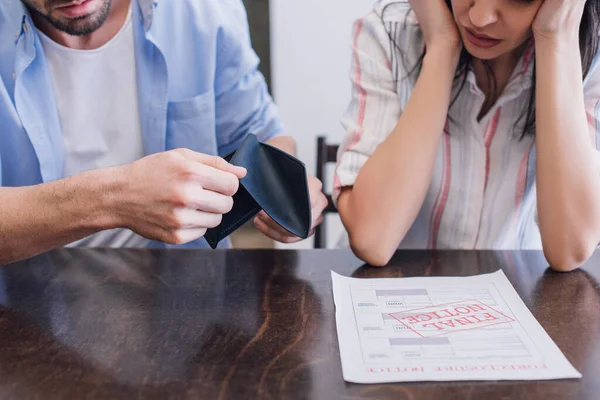 Cropped view of man holding purse near woman at table with document with final notice lettering in room — Stock Photo