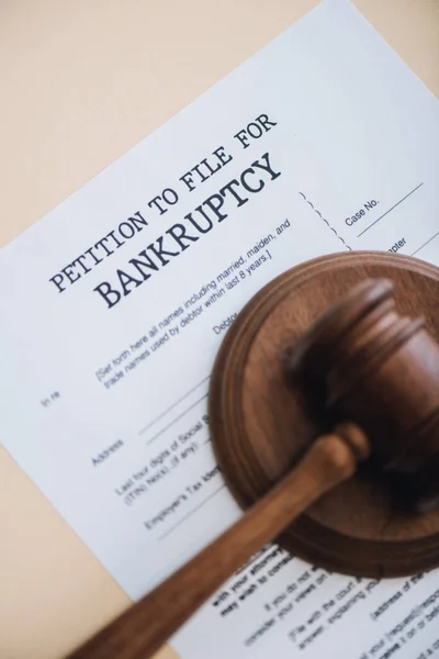 Top view of gavel on document with petition to file for bankruptcy lettering isolated on beige — Stock Photo