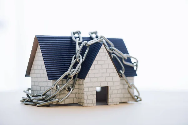 Modelo de casa con cadena metálica aislada en blanco - foto de stock
