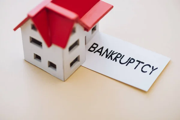 High angle view of card with bankruptcy lettering and house model on white — Stock Photo