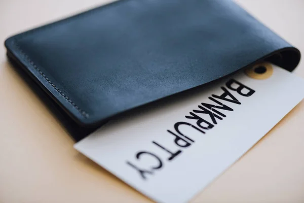 Monedero negro y tarjeta con letras de bancarrota en blanco - foto de stock