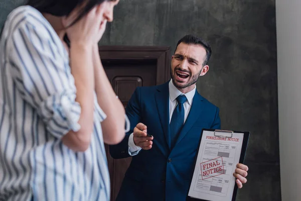 Selektiver Fokus des wütenden Sammlers mit Dokumenten mit Zwangsvollstreckung und endgültiger Kündigung Schriftzug schreit und zeigt auf Frau — Stockfoto