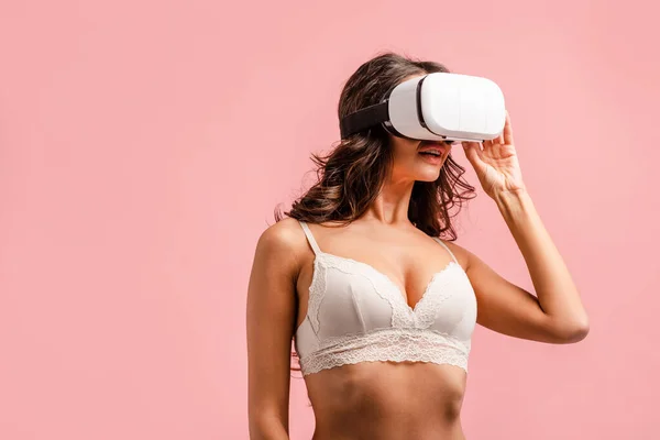 Femme chaude en soutien-gorge avec casque de réalité virtuelle isolé sur rose — Photo de stock