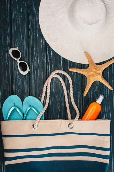 Top view of starfish, flip flops near sun hat and sunglasses on dark wooden surface — Stock Photo